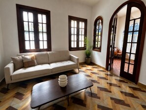 A living room with a sofa, a coffee table, and a potted plant.