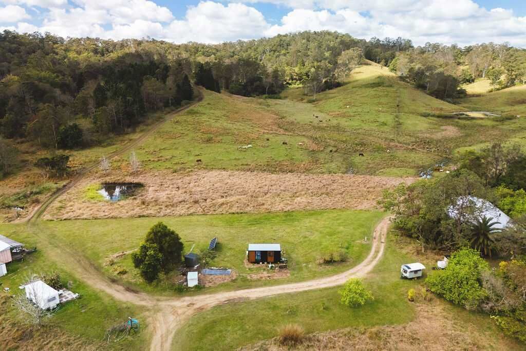 A rural landscape with a small house, a dirt path, and a pond.