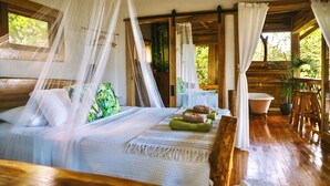 Une pièce aux murs en bois, avec un lit, une baignoire et une petite table sur laquelle sont posées des serviettes.