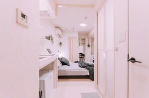 A narrow hallway with a bed, a desk, and a wardrobe. - Minimalist Loft 303 (Osaka)
