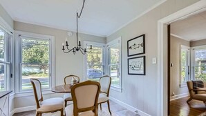 A dining area with a round table and four chairs, large windows, and a chandelier. - Sweet Sage Cottage in Old Town Close to the Square (Georgetown)