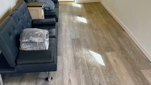 A room with a dark-colored sofa, a wooden floor, a white door, and windows with natural light. - Spacious 8-bedroom building in welcoming Fairbanks with WiFi (Fairbanks)