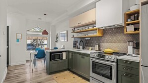 Una cocina moderna con armarios grises, electrodomésticos de acero inoxidable y un estante de madera.