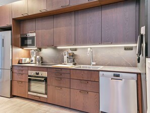 A modern kitchen with stainless steel appliances, wooden cabinets, and a built-in oven.