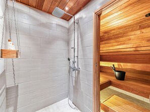 Un baño moderno con ducha, paneles de madera y un estante con artículos de aseo.