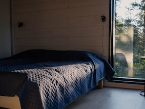 Un dormitorio con cama, ventana y vistas a árboles y un puente.