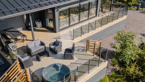 Une terrasse extérieure moderne, dotée d’un espace salon et d’un jacuzzi.