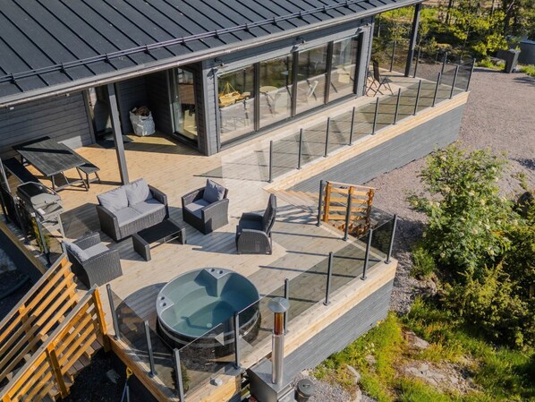 A modern outdoor deck with seating and a hot tub.