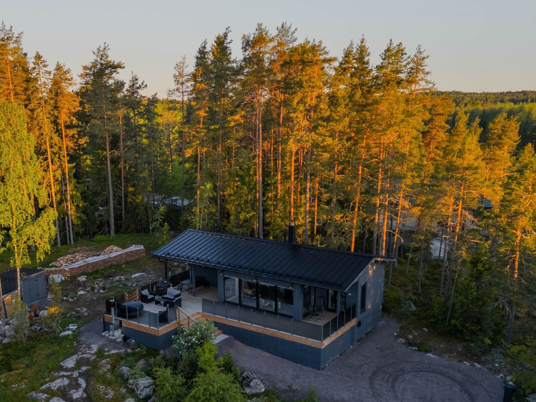Eine moderne Hütte mit einer Terrasse, umgeben von einem Wald.