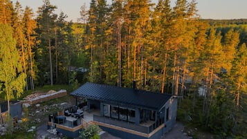 Eine moderne Hütte mit einer Terrasse, umgeben von einem Wald.