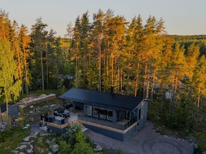 Una cabaña moderna con terraza, rodeada de bosque.