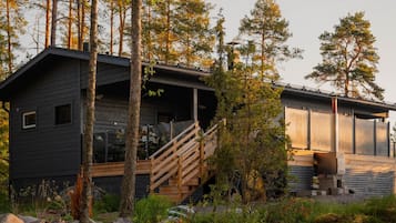 Eine moderne Holzhütte mit einer Holzterrasse und einer Treppe zu einer überdachten Veranda.
