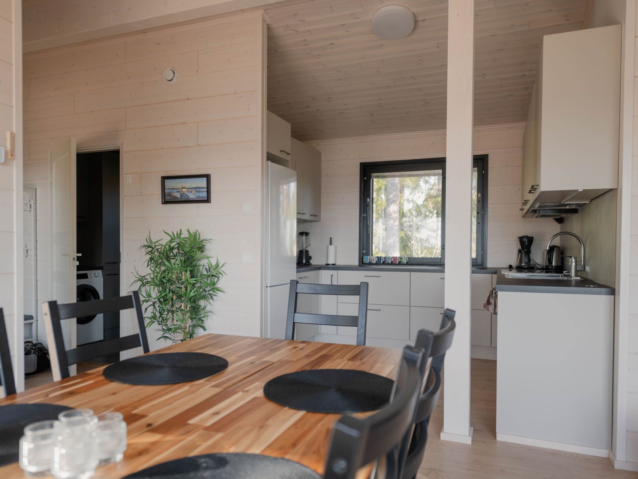 A modern kitchen with white cabinets, a black countertop, and a window.