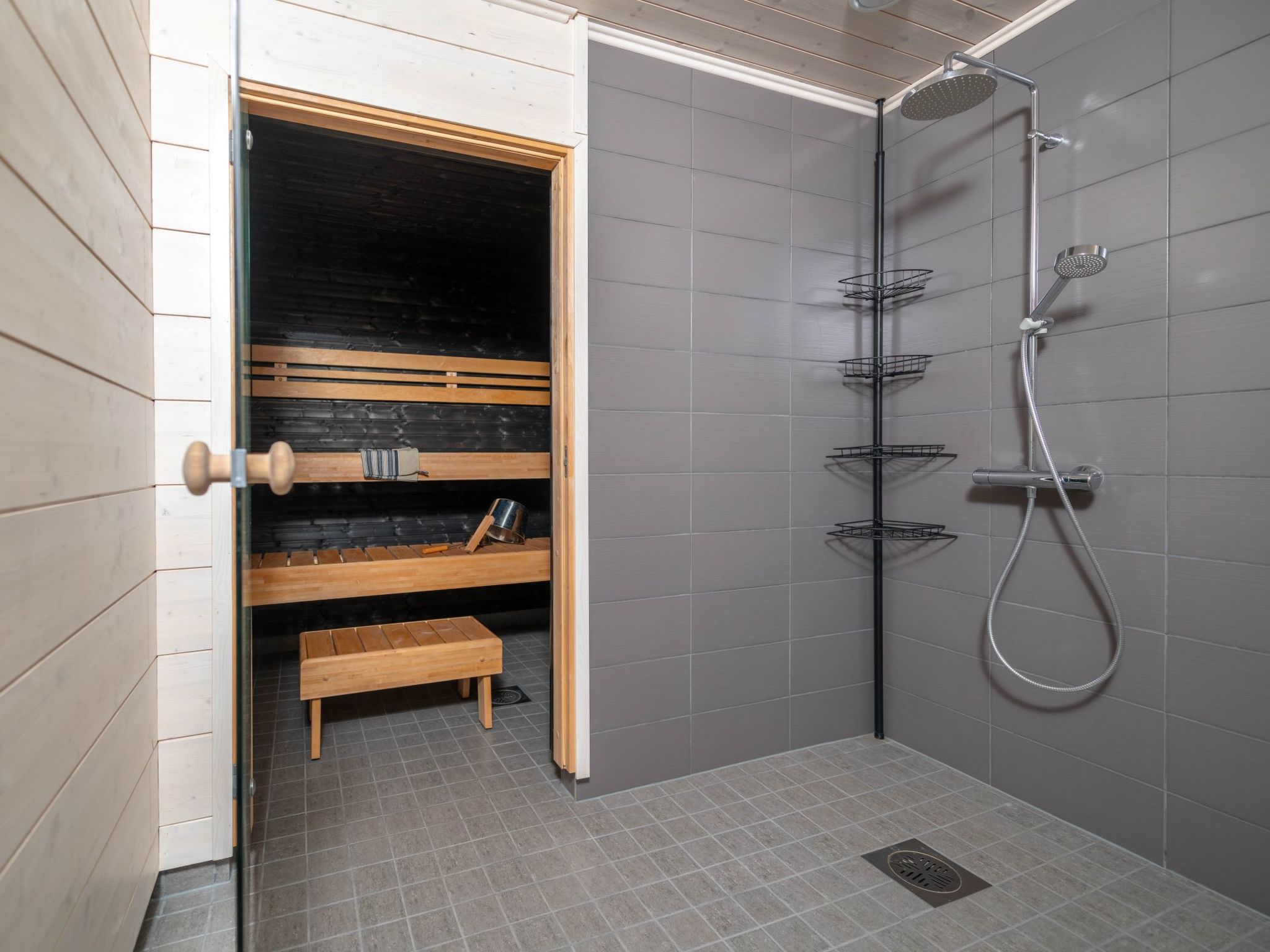 Un bagno moderno con doccia, una panca di legno e uno scaffale con articoli da toilette.