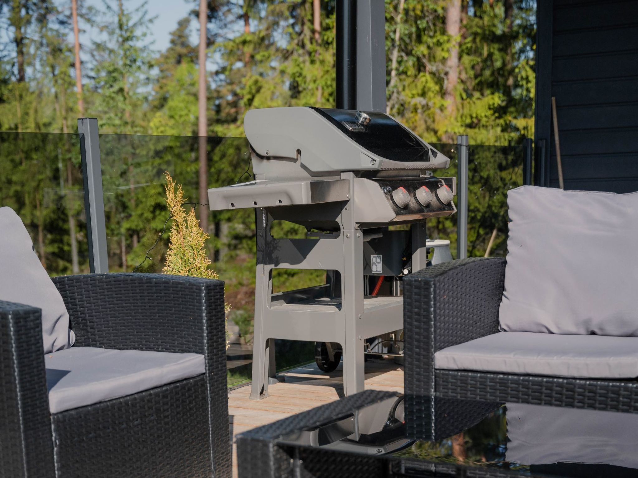 An outdoor seating area with wicker furniture and a barbecue grill.