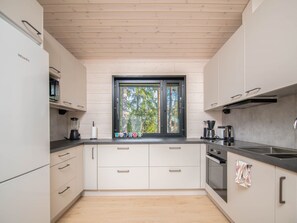 A modern kitchen with white cabinets, a black countertop, and a window with a view of trees. - Sjöboda hill by Interhome (Inkoo)
