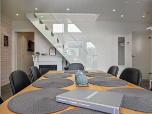 A modern dining area with a wooden table, grey placemats, and a book titled 'Möskikansio | Handbook | Sprawočnik'. - Himos alppinotko 6 b by Interhome (Kuhmoinen)