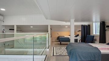 Quarto moderno com varanda de vidro, uma cama, uma poltrona e uma escrivaninha.