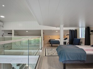 A modern bedroom with a glass balcony, a bed, a chair, and a desk.