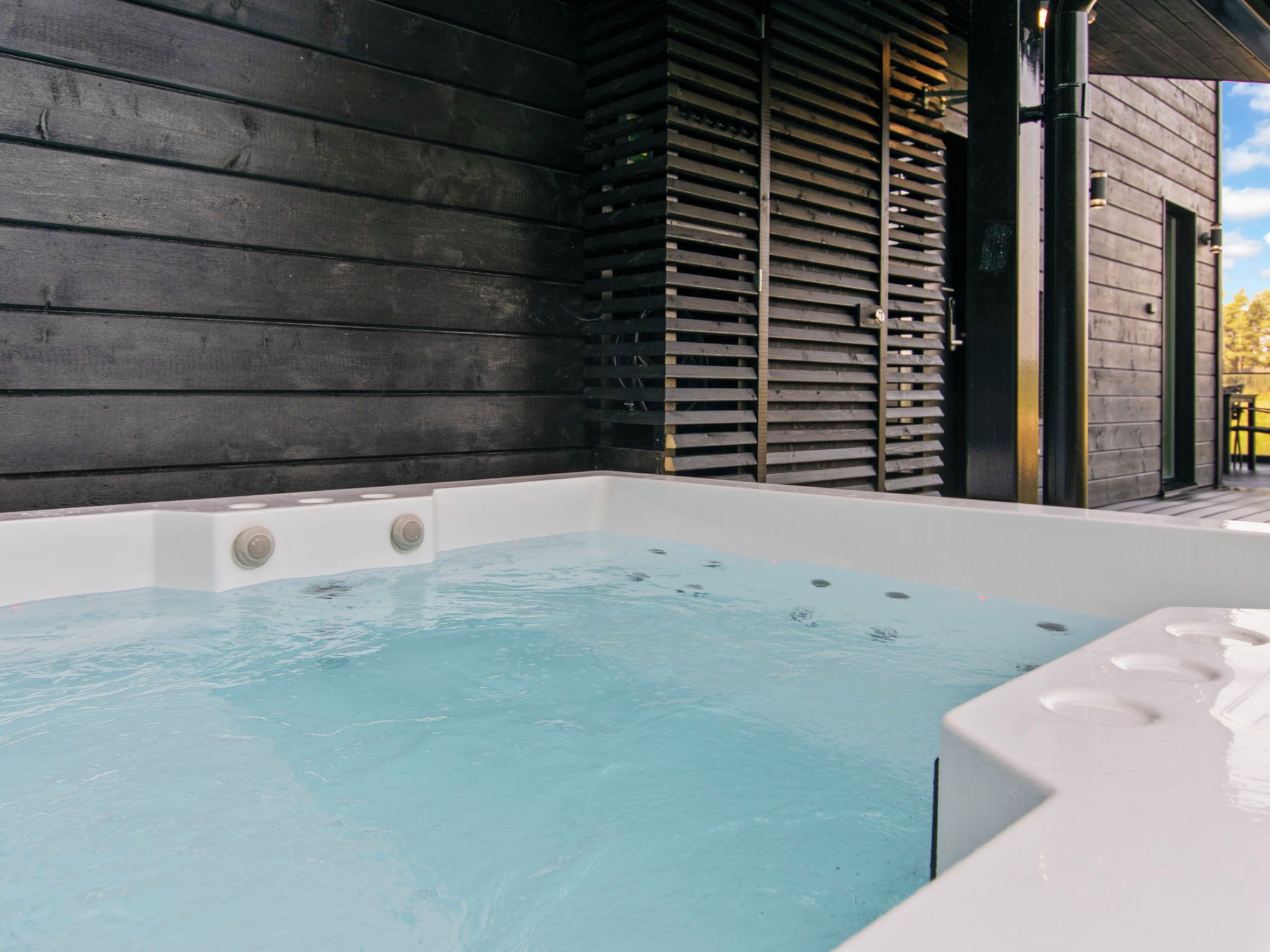 A hot tub with a wooden exterior wall and a door leading to an outdoor area.