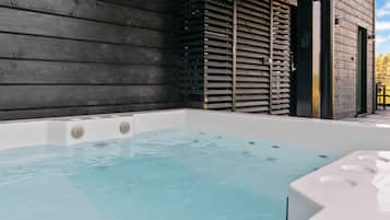 A hot tub with a wooden exterior wall and a door leading to an outdoor area.