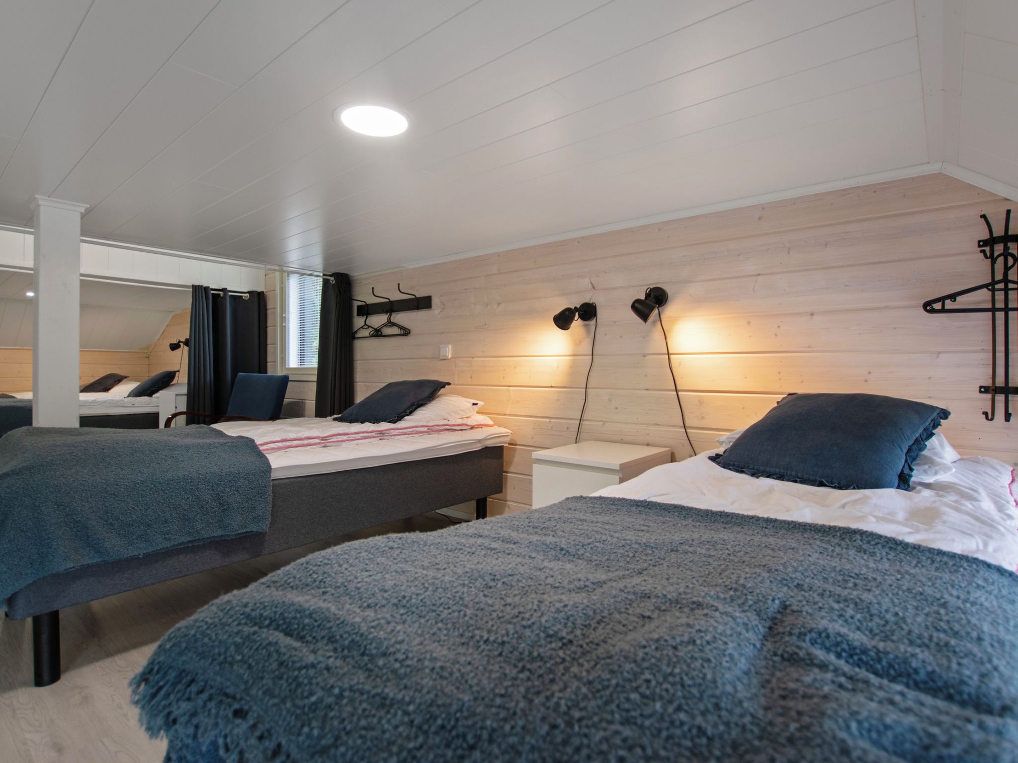 Un dormitorio moderno con dos camas, una pared de madera y un espejo.