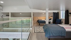 A modern hotel room with a large bed, a desk, and a glass balcony.