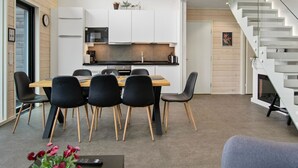 A modern kitchen with white cabinets, a black countertop, and a dining area with a wooden table and black chairs.