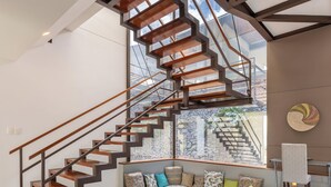 A modern interior with a spiral staircase, a seating area with cushions, and a patterned rug.