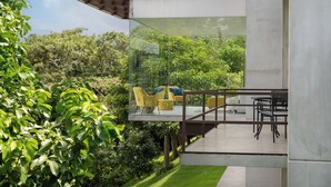 A modern outdoor patio with glass walls, a wooden deck, and outdoor furniture.