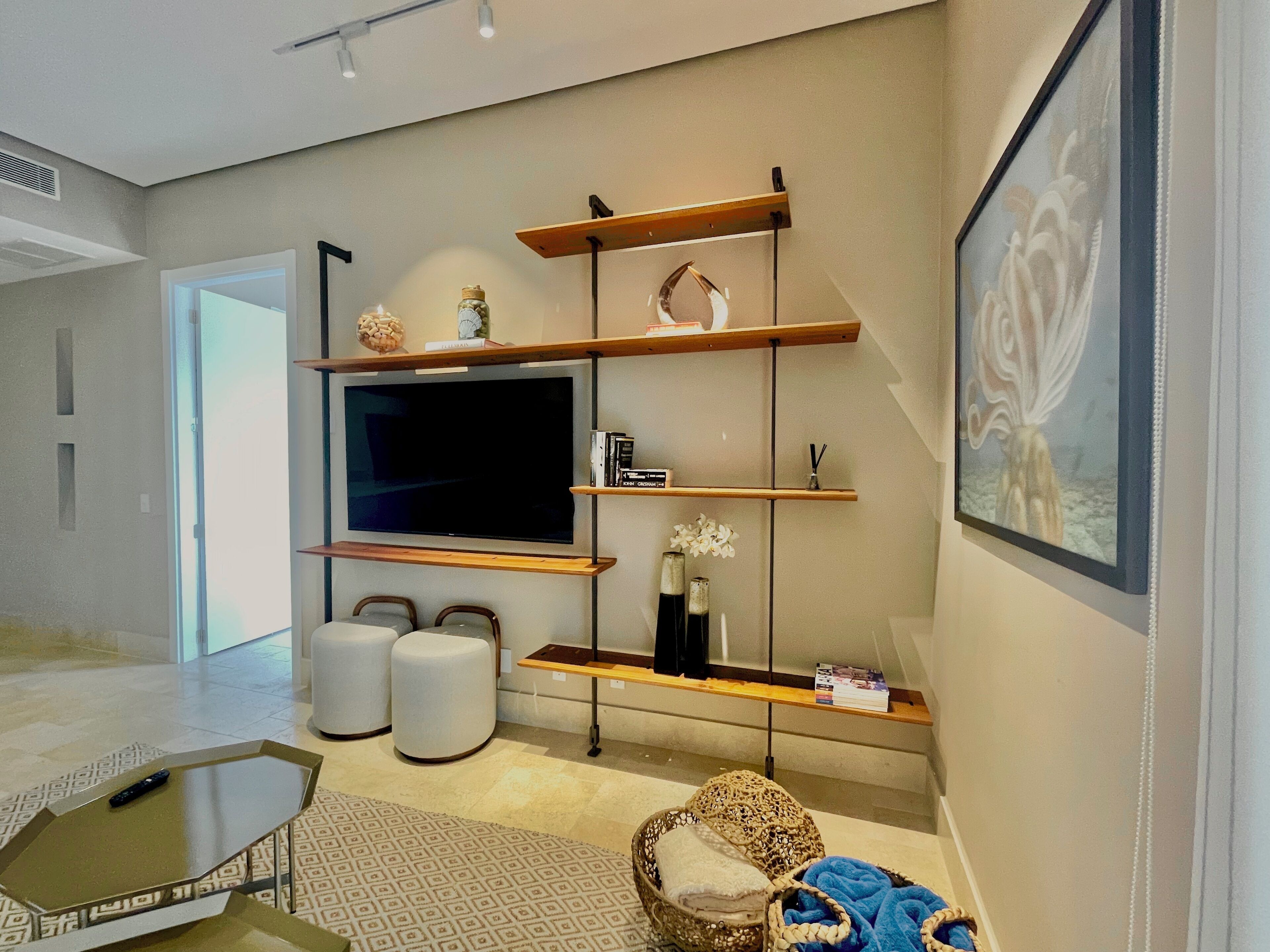 A modern living room with a large flat-screen TV, built-in shelves, a coffee table, and a comfortable seating area.