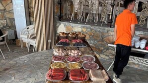 Une table de buffet garnie de différents plats, et une personne portant un t-shirt orange se tenant à proximité.