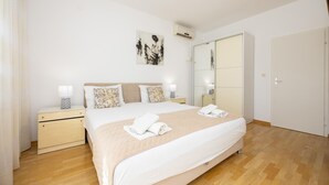 A neatly arranged bedroom with a bed, bedside tables, a wardrobe, and an air conditioning unit. - Nice apartment in Dugi Rat with WiFi (Dugi Rat)