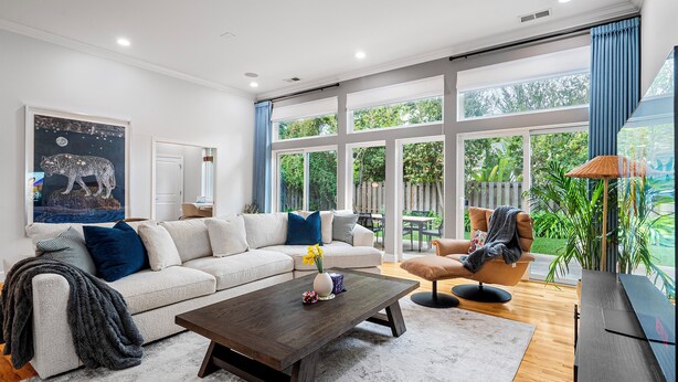A modern living room with a large window, a sofa, a coffee table, and a TV.