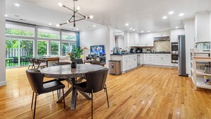 A spacious kitchen with wooden flooring, white cabinets, and a central island.