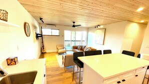 A modern kitchen with a central island, a dining area with a table and chairs, and a living space with a sofa and a guitar. - Spacious 3-bedroom/ 2 bath apartment in Topanga Hills with AC (Topanga)