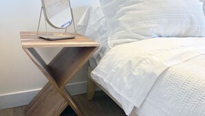 A bed with white bedding, a wooden bedside table with a mirror, and a wooden floor. - Spacious 3-bedroom/ 2 bath apartment in Topanga Hills with AC (Topanga)