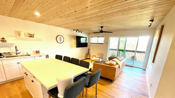 A spacious kitchen with a central island, a dining area with bar stools, a living room with a sofa and a guitar, and a balcony with a view. - Spacious 3-bedroom/ 2 bath apartment in Topanga Hills with AC (Topanga)
