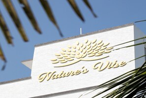 A sign with the text "Nature's Vibe" and a stylized leaf design. - Natures Vibe Beach Resort (Cheyyur)