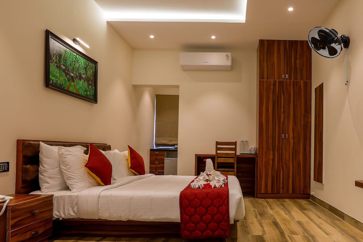 Une chambre avec un lit en bois, un plaid rouge, une armoire en bois et un ventilateur de plafond.