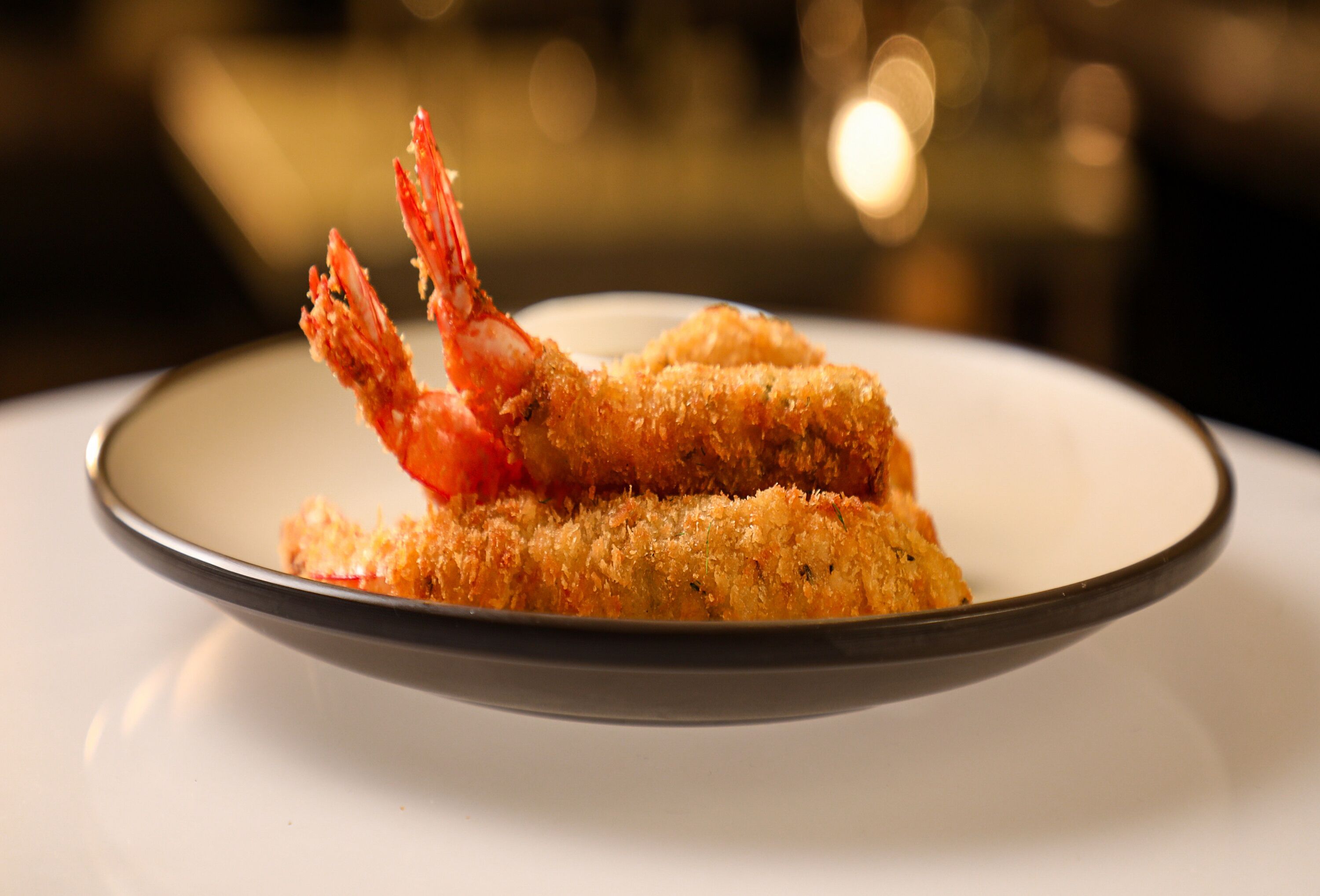 A plate with two breaded shrimp and a sauce.