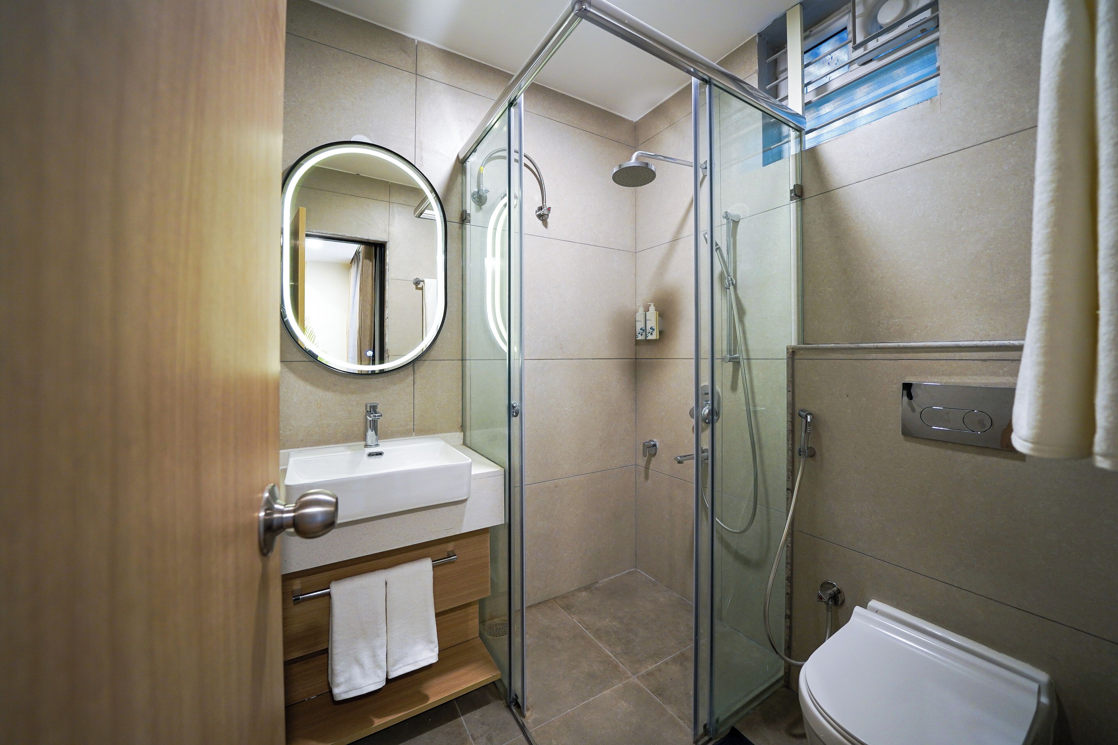 A modern bathroom with a glass-enclosed shower, a sink with a mirror, and a toilet.