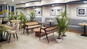 A modern lounge area with seating arrangements, potted plants, and wall art.