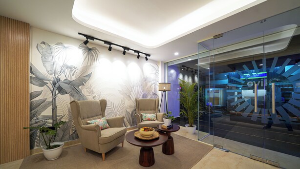 A modern lounge area with a large wall mural, comfortable seating, a coffee table, and a potted plant.