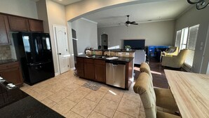 A spacious kitchen with a central island, a dining area with a wooden table and chairs, and a ceiling fan. - Cypress Moss Retreat in Legacy 4BR 2BA (Bossier City)