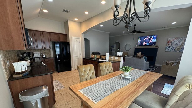 A modern kitchen with dark wood cabinets, a stainless steel refrigerator, and a built-in oven. - Cypress Moss Retreat in Legacy 4BR 2BA (Bossier City)