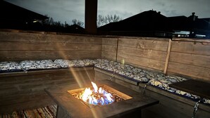 A fire pit in a wooden outdoor seating area with benches. - Cypress Moss Retreat in Legacy 4BR 2BA (Bossier City)