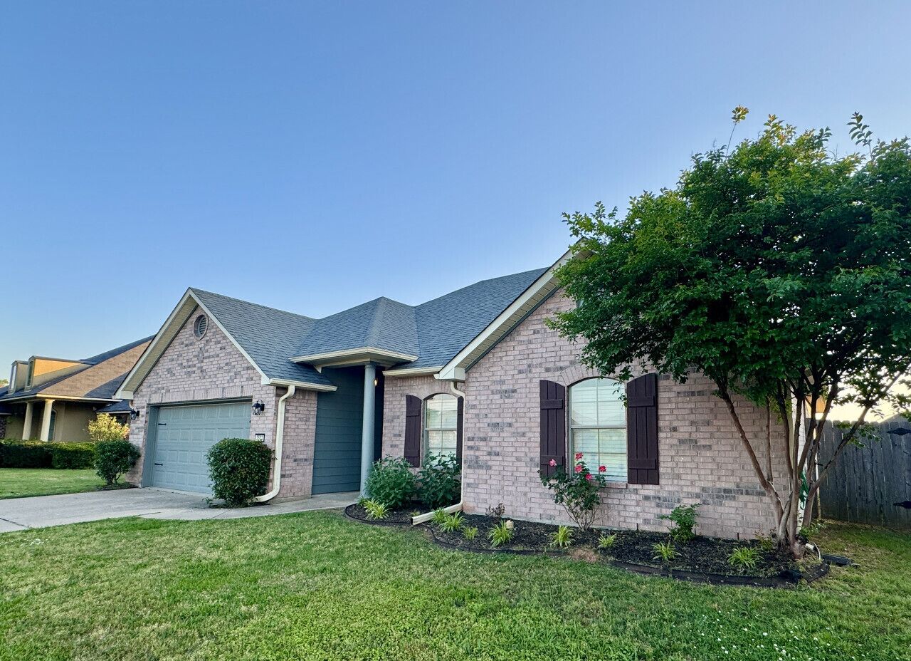 A two-story house with a brick exterior, a front garage, and a well-maintained lawn.