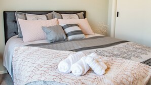 A neatly made bed with a quilted cover, pillows, and rolled towels. - Modern Contemporary Single Detach Home (Wellington)