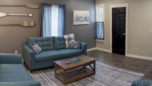 A living room with a blue sofa, a wooden coffee table, and a patterned rug. - Newly Renovated Acadia Apartment Maple Street (Ellsworth)